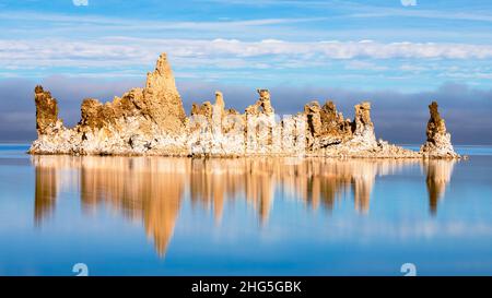 Große Tuffsteinformation in Mono Lake im Mono County, Kalifornien, USA. Das Bild zeigt Reflexionen und launische/niedrige Wolken im Hintergrund. Stockfoto