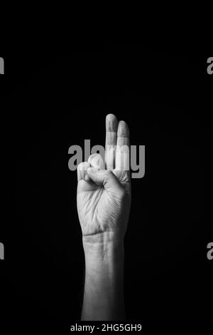 Dramatische s+W-Bild der männlichen Hand Fingerbuchstabierung CSL chinesischen Zeichen Sprache Buchstaben H isoliert vor dunklem Hintergrund Stockfoto