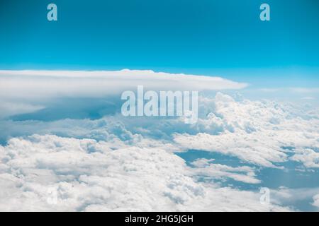 Weiße geschwollene Wolken aus einem sich bewegenden Flugzeug. Blauer Himmel oben. Fliegen in der Luft. Flugreise. Hochwertige Fotos Stockfoto