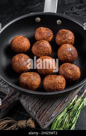 Gebratene Fleischbällchen auf pflanzlicher Basis in einer Pfanne mit Kräutern. Schwarzer Hintergrund. Draufsicht Stockfoto