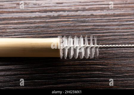 Nahaufnahme der Verwendung einer Trinkhalm-Reinigungsbürste zur Reinigung von wiederverwendbarem Bambus-Trinkhalm in Innenräumen zu Hause. Stockfoto
