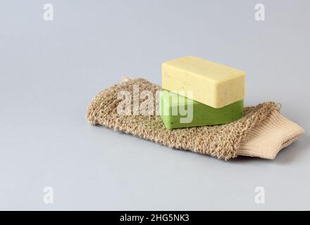 Körperwaschtuch aus Naturfasern und zwei Naturseifen auf blauem Hintergrund. Konzept von Hygiene und Sauberkeit Stockfoto