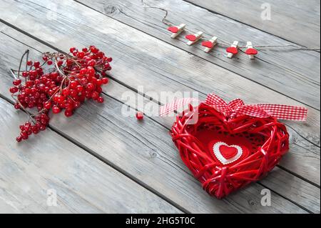 Geflochtenes Herz auf einem hölzernen Hintergrund. Herz aus getrockneten Zweigen von handgefertigten Trauben gewebt ist ein Hintergrund für Herzlichen Glückwunsch. Stockfoto