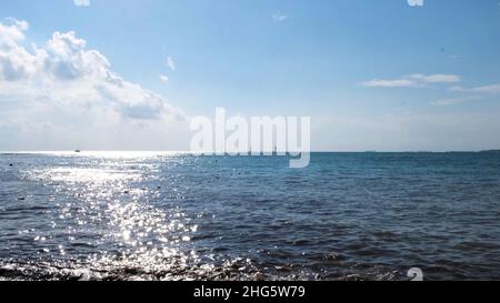 Sommer natürliche Landschaft mit welligen Meeresoberfläche scheint hell auf blau bewölkten Himmel Hintergrund. Die Sonne spiegelte sich an einem sonnigen Sommertag im Wasser. Stockfoto