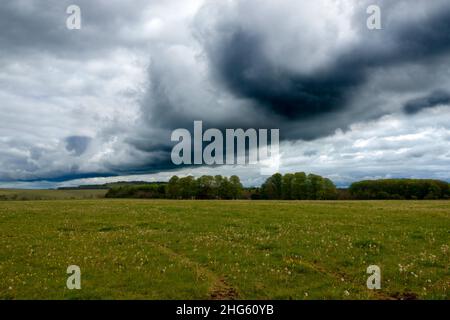 Eine dunkelschwarze Regalwolke in einem vorhersehenden dunkelgrauen Gewitterwolkenhimmel, der starken Regen über die offene Landschaft bringt Stockfoto