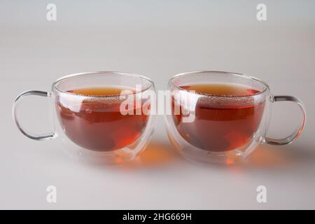 Teetrinken. Zwei transparente doppelwandige Tassen mit frisch gebrühtem schwarzem Tee. Das Konzept des Minimalismus. Stockfoto