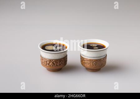 Zwei traditionelle Kaffeetassen werden mit frisch gebrühtem türkischen Kaffee gefüllt. Das Konzept des Minimalismus. Stockfoto