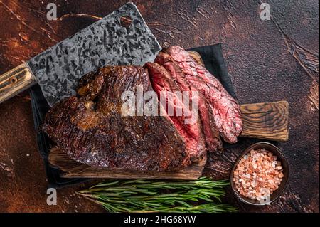 Gebratenes, hängendes, zartes oder in Scheiben geschnittenes Rindersteak auf einem Fleischbrett mit Hackschnitzel. Dunkler Hintergrund. Draufsicht Stockfoto