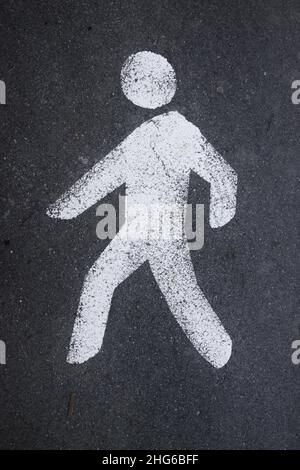 Bild eines Verkehrszeichens in Form eines Fußgängers auf dem Asphalt, das auf eine Fußgängerzone hinweist Stockfoto
