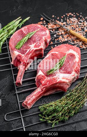 Frische, rohe Tomahawk-Steaks mit Rippenauge auf dem Grill. Schwarzer Hintergrund. Draufsicht Stockfoto