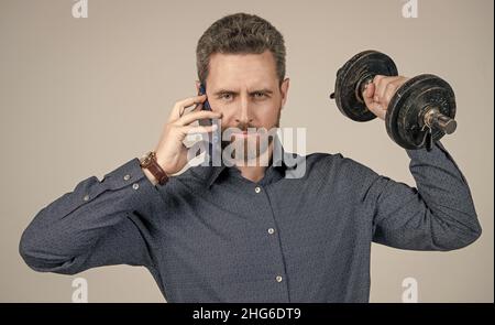 Gutaussehender Geschäftsmann mit Hantel sprechen am Telefon. Digitaler Sport. Stockfoto