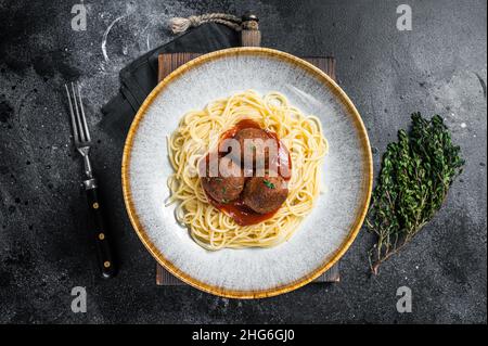 Vegetarische Pasta mit fleischlosen Fleischbällchen aus Fleisch- und Tomatensauce auf pflanzlicher Basis. Schwarzer Hintergrund. Draufsicht Stockfoto