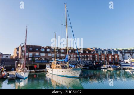 Segelboote, die an Apartments am Wasser in Camber Quay in Portsmouth Harbour, Hampshire, Südküste Englands, festgemacht sind Stockfoto