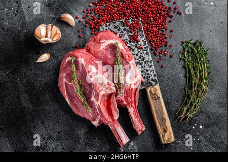 Rohe Tomahawk Rib Kalbssteaks auf Fleischspalter. Schwarzer Hintergrund. Draufsicht Stockfoto