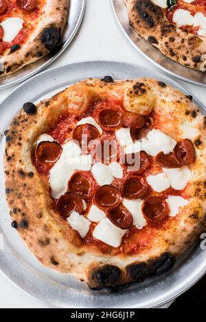 Frische Pizzapasteten mit Pepperoni auf Tabletts Stockfoto