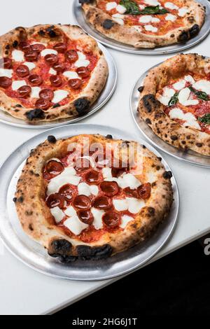 Frisch gebackene Pizzapasteten von Margherita und Pepperoni auf Tabletts Stockfoto