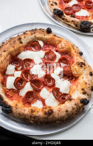 Frische Pizzapasteten mit Pepperoni auf Tabletts Stockfoto