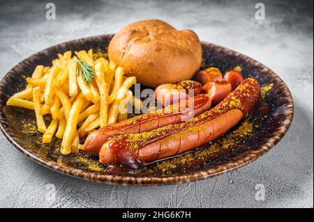 Currywurst, Würstchen mit Currysauce und Pommes frites. Weißer Hintergrund. Draufsicht Stockfoto