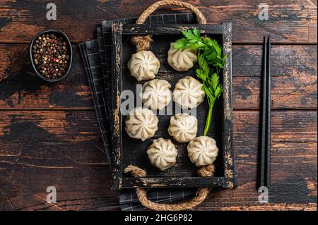 Momo Knödel in einem Holztablett mit Kräutern. Dunkler Holzhintergrund. Draufsicht Stockfoto