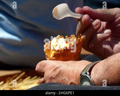 Männliche Hände halten Eiskegel und Löffel Stockfoto