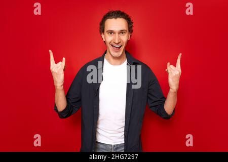 Aufgeregt Mann mit seinem Mund offen zeigt Rock-Schild mit seinen Händen zeigt hören Lieblingsmusik Stockfoto