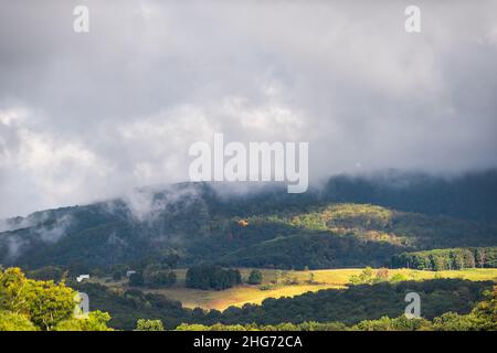 Morgen gelber Sonnenaufgang Sonnenlicht dramatische stürmische neblige Wolken Himmel Herbstlaub Herbstsaison in den Bergen von West Virginia in der Nähe von Wardensville mit Farm-Fie Stockfoto