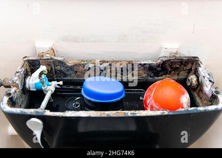 In der kaputten Toilette in der Nähe öffnen, mit Rost verschmutzt, schmutzige alte Materialpumpe und Wasser in einem kleinen Badezimmer in London, Großbritannien Stockfoto