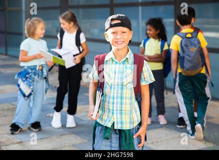 Lächelnder Grundschuljunge, der im Freien steht Stockfoto