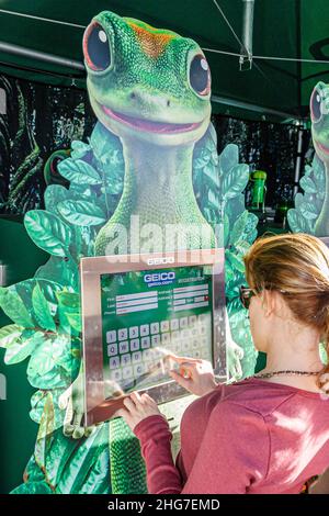 Miami Florida, Coconut Grove, Arts Festival, GEICO Autoversicherung, Touchscreen-Umfrage zum Ausfüllen des Fragebogens, Gecko-Maskottchen-Logo, Frau, die antwortet Stockfoto