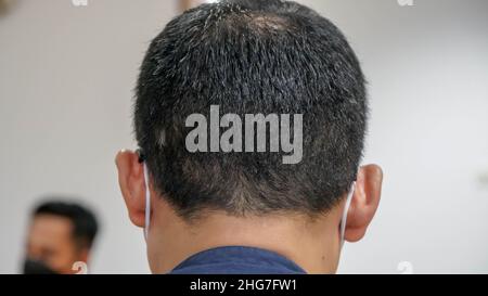 Asiatischer Mann, von hinten gesehen, im Kopf mit schwarzem Haar im selektiven Fokus Stockfoto