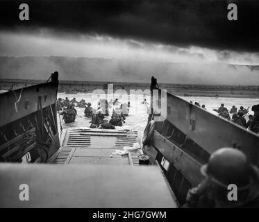 Die D-Day Landungen - ein Blick aus dem Inneren eines Landungsschiffes, das Männer des Infanterie-Regiments 16th, US 1st Infantry Division, zeigt, die am Omaha Beach mit dem rauchbedeckten Strand dahinter an Land wateten Stockfoto