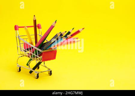 Buntstifte im Warenkorb auf gelbem Hintergrund.Schulbedarf zum Zeichnen Stockfoto
