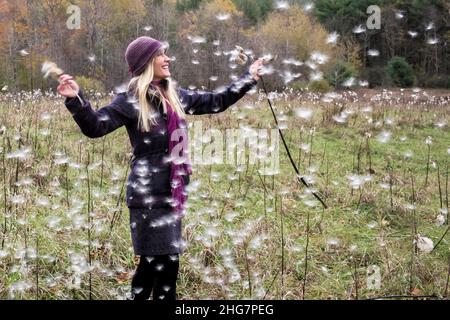 Blonde Frau, die im Feld der Blasen des Dandelions steht Stockfoto