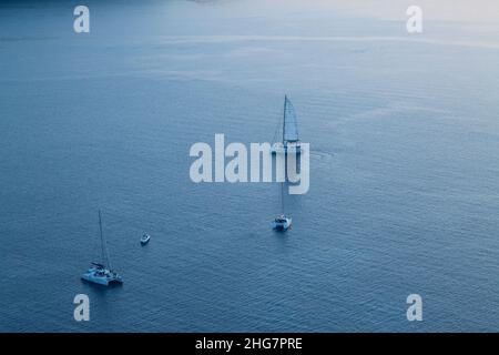 Drei Katamarane und ein Motorboot auf dem Wasser in Santorini, Gr Stockfoto