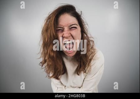 Nahaufnahme Porträt einer verrückten Frau in Zwangsjacke auf weißem Hintergrund. Stockfoto