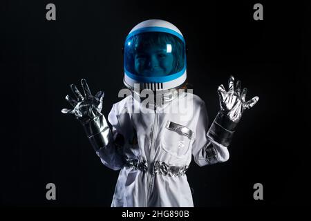 Das kleine Kind will einen in den Weltraum fliegen, der einen Astronauten-Helm auf Schwarz trägt. Speicherplatz kopieren. Stockfoto