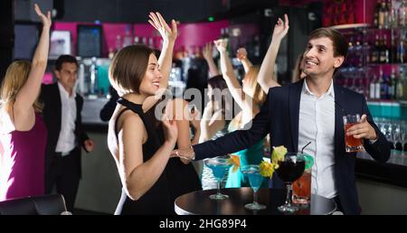 Kollegen tanzen auf Corporate Party mit Cocktails in Händen Stockfoto