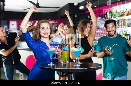 Männchen mit zwei Weibchen sprechen und trinken Cocktails Stockfoto