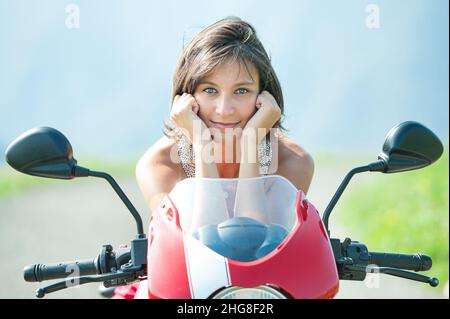Nahaufnahme eines wunderschönen dunkelhaarigen Mädchens auf dem Motorrad Stockfoto