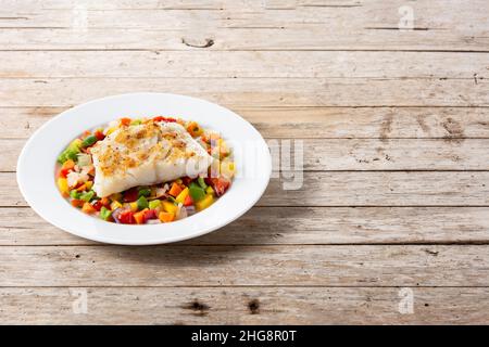 Gegrillter Kabeljau mit Gemüse in Teller auf Holztisch Stockfoto