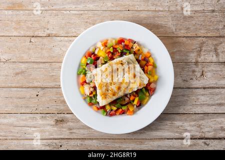 Gegrillter Kabeljau mit Gemüse in Teller auf Holztisch Stockfoto