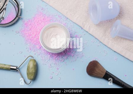 Flatlay mit Creme, Bad Rose Salz, Massage Vakuum Gläser auf blu Hintergrund.Spa und natürliche Hautpflege-Konzept Stockfoto