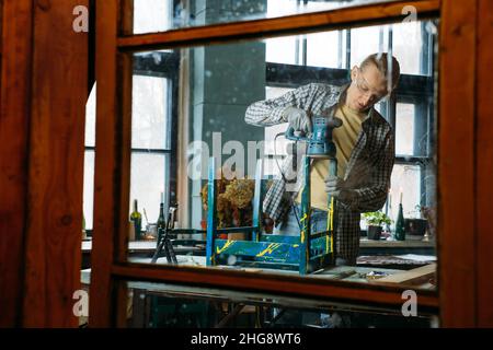 Mann, der in der Werkstatt arbeitet, Möbel macht, alte Materialien zu neuen Produkten wiederverwenden. Kleines, ökokriegliches Unternehmen. Recycling Stockfoto