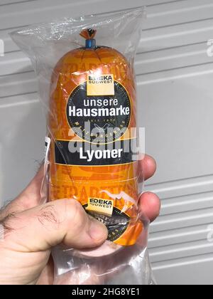 Paris, Frankreich - 7. Jan 2022: POV männliche Handpackage mit Lyoner Edeka-Wurst - leckeres deutsches Essen Stockfoto