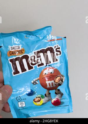 Paris, Frankreich - 7. Jan 2022: POV männliche Hand hält Plastikpaket mit M und M gesalzenem Karamell Süßigkeiten Bonbons Süßigkeiten Stockfoto