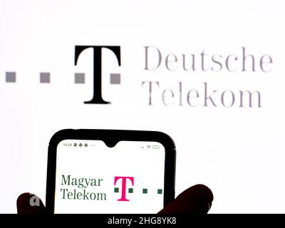 In dieser Abbildung ist das Logo der Magyar Telekom Telecommunications Public Limited Company auf einem Smartphone-Bildschirm mit dem Logo der Deutschen Telekom AG im Hintergrund zu sehen. Stockfoto