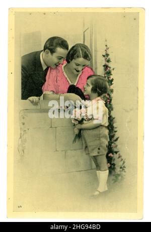 In Frankreich gedruckte französische getönte Grußkarte aus den 1920er Jahren, kitschig, von einem Kind, das Mutter und Vater Rosen schenkte. Stockfoto