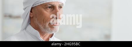 Porträt eines bärtigen muslimischen Mannes in weißem Turban, der nach Hause schaut, Banner Stockfoto