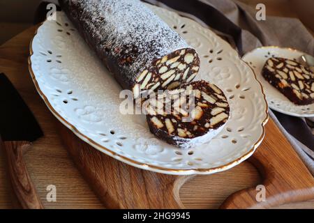 Fauler Kuchen oder Mosaikkuchen . Hausgemachter, nicht gebackener Schokoladenkuchen auf einem Holztisch Stockfoto