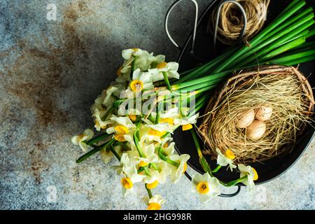 Ansicht von oben auf Narcissus Blumen neben drei Eiern in einem Vogelnest Stockfoto